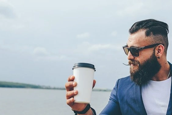 Man holding coffee wearing blazer near waterfront
