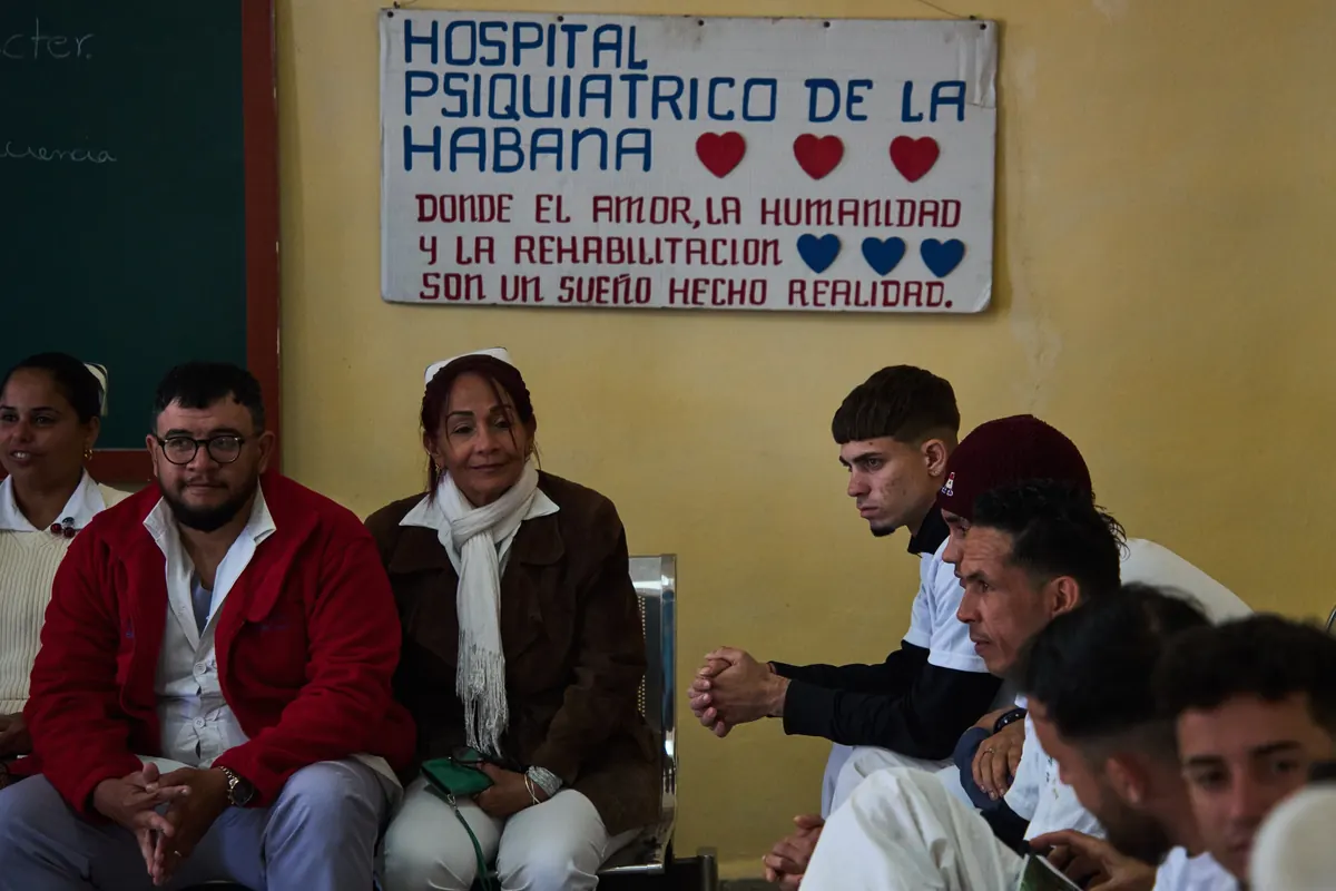 Medical staff, left, and people in rehabilitation, right, sit at a psychiatric hospital in Havana, Cuba