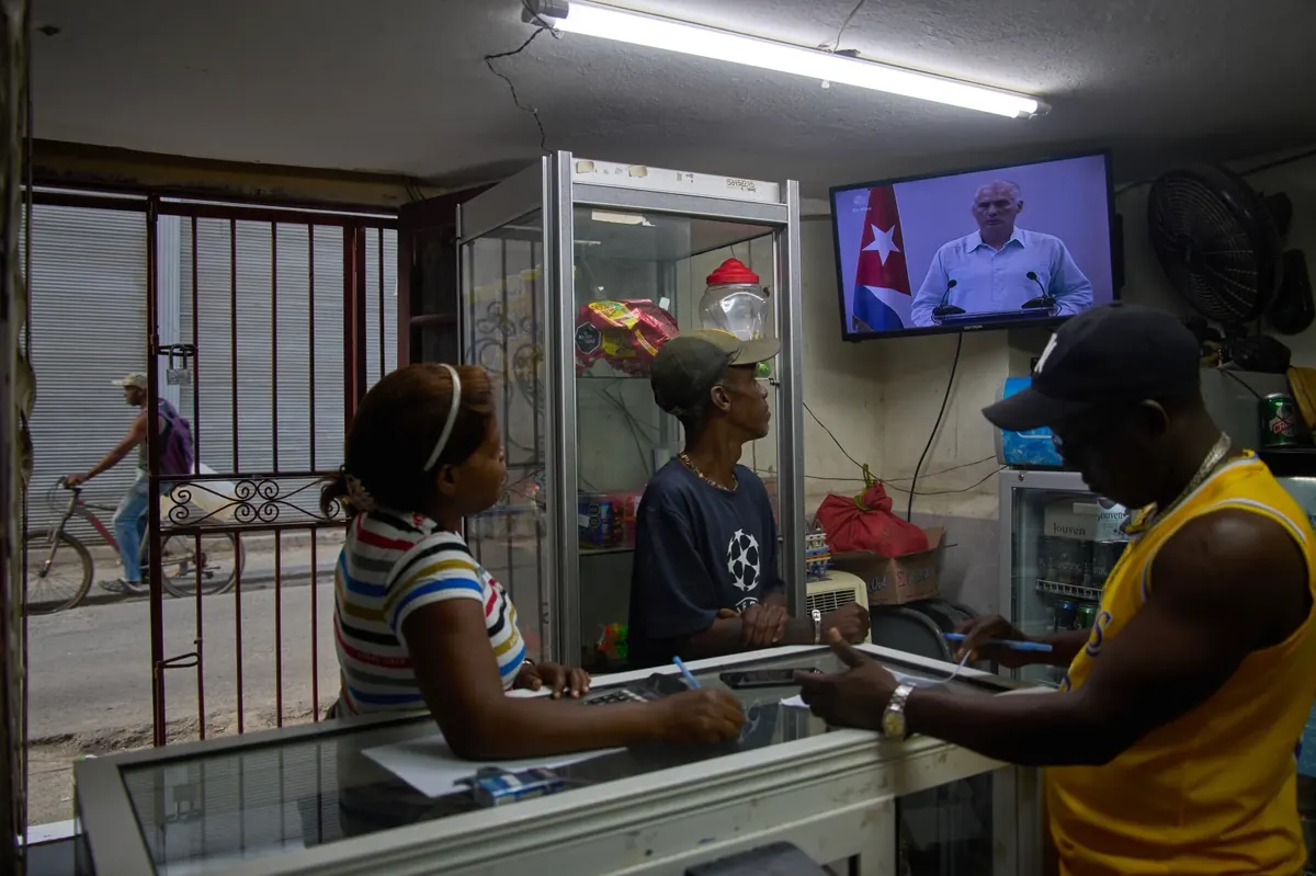 People inside a private convenience store see Cuban President Miguel Diaz-Canel speaking on TV in Havana, Cuba